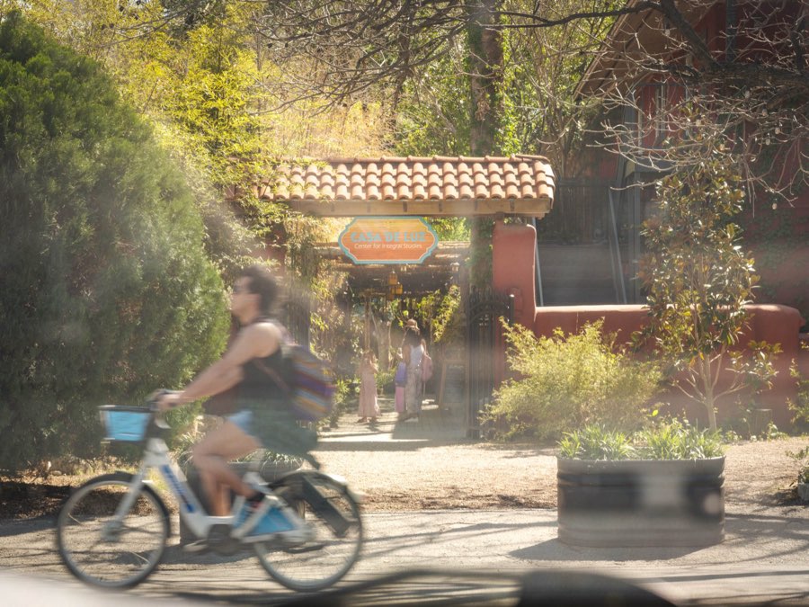 The shaded entrance arbour at Casa de Luz with people walking in from the street