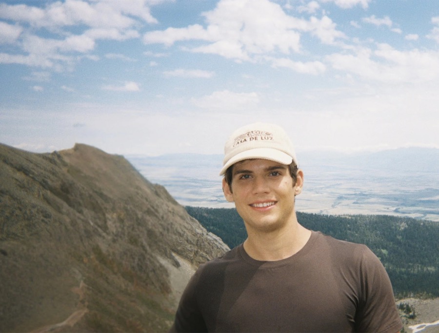 Gabriel Longoria on a mountain ridge wearing a Casa de Luz cap